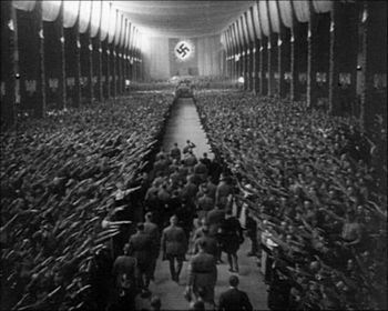Кадр из фильма. Гитлер возглавляет делегацию высокопоставленных нацистов, заходящую в зал собраний.